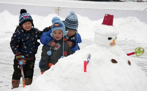 12月14日,在河北省承德市,三個小朋友雪人旁玩耍。新華社記者 王昆 攝