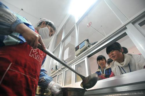 在廣西桂林市龍勝各族自治縣初級(jí)中學(xué)食堂,一名工作人員在給寄宿就讀學(xué)生打早餐(12月5日攝)。新華社記者陸波岸攝