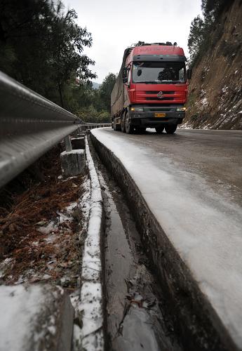 1月6日,在廣西桂林市資源縣資源鎮(zhèn)通往湖南的資梅公路上,一輛貨車在結(jié)冰的道路上緩慢行駛。新華社記者 陸波岸 攝