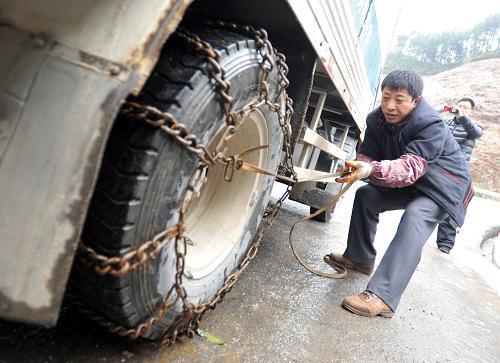 1月6日,在廣西桂林市資源縣資源鎮(zhèn)通往湖南的資梅公路上,一名男子在給汽車裝上防滑鏈,準備通過結(jié)冰道路。新華社記者 陸波岸 攝