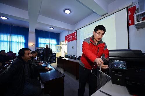 1月15日,黃南藏族自治州第一民族中學內(nèi),格?;ń逃戎鷷x工刑光偉在為受捐助學校老師講解打印機的操作方法。新華社發(fā)(吳剛 攝)