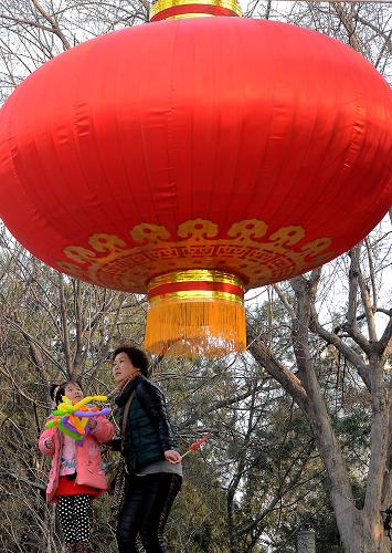 2月9日,一位女士帶著孩子從鄭州一休閑廣場(chǎng)的大燈籠下經(jīng)過(guò)。新華社記者 王頌 攝