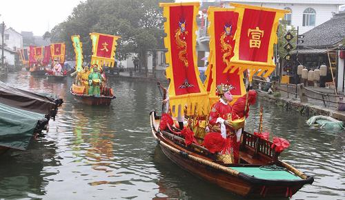 2月14日,“財(cái)神”在水鄉(xiāng)周莊舉辦的“財(cái)神節(jié)”民俗表演活動上為商家巡游“送福”。新華社發(fā)(朱桂根 攝)