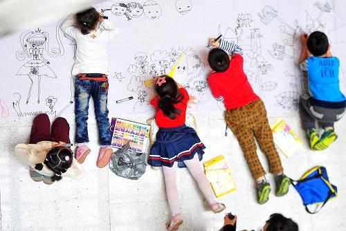 6月1日,在湖北圖書館舉行的“我的中國夢,最美東西湖”少兒書畫作品展上,孩子們在長卷上畫畫。新華社記者 肖藝九 攝