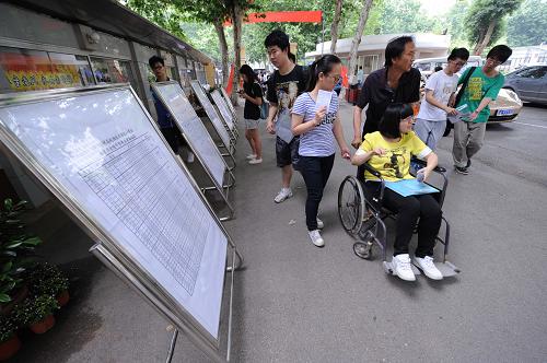 6月6日,在南京金陵中學(xué)考點(diǎn),一名坐輪椅的考生從考場安排圖展示板前經(jīng)過。新華社記者 孫參 攝