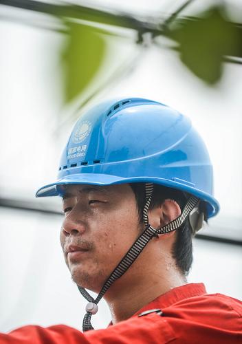 6月19日,浙江省長(zhǎng)興縣供電局工作人員陳源冒著高溫在呂山鄉(xiāng)龍溪村檢查用電設(shè)備,保障夏季農(nóng)村用電。新華社記者 徐昱 攝