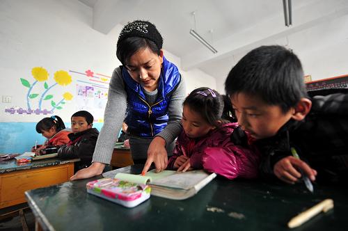 12月6日,甘肅省積石山保安族東鄉(xiāng)族撒拉族自治縣吹麻灘小學(xué)的一名教師正在課堂上輔導(dǎo)學(xué)生功課。新華社記者 張錳 攝