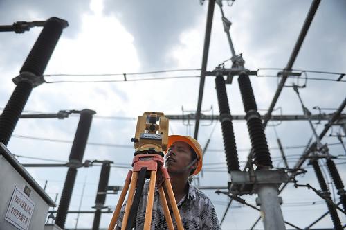 江西萍鄉(xiāng)一位電力公司工人在為變電站擴(kuò)建工程進(jìn)行測(cè)繪(2012年7月12日攝)。新華社記者 周密 攝