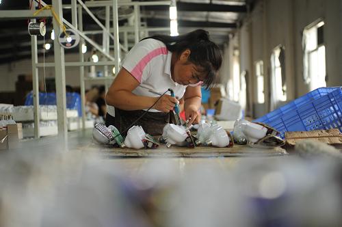 江西靖安一家照明企業(yè)的女工在流水線上工作(2012年6月28日攝)。新華社記者 周密 攝
