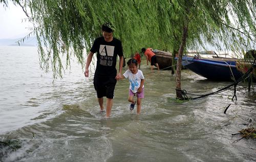 8月14日,市民在鄱陽(yáng)湖星子段一處淹沒(méi)的圩堤上玩耍。新華社記者 周科 攝