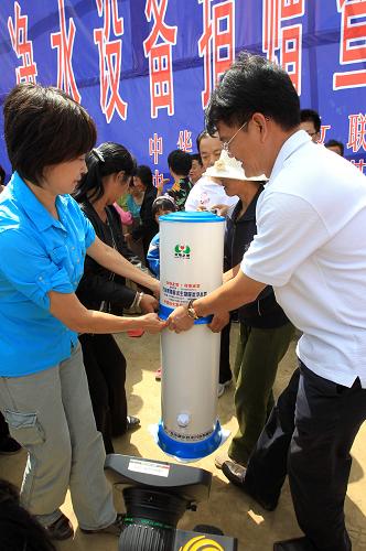 8月22日,“母親水窖”形象大使敬一丹(左)、完美(中國)有限公司總裁胡瑞連(右)在凈水設(shè)備捐贈儀式上為村民發(fā)放凈水器。新華社記者 李明放 攝