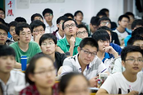 高考夢工廠 毛坦廠中學(xué)內(nèi),高三學(xué)生在課堂上(5月23日攝)。 安徽省六安市毛坦廠鎮(zhèn)毛坦廠中學(xué)(包括其復(fù)讀校金安中學(xué),文中統(tǒng)稱為毛坦廠中學(xué))雖然是一所地處大別山山坳的鄉(xiāng)鎮(zhèn)級高中,但擁有學(xué)生近兩萬人,其中高三學(xué)生萬余人。近年來,這所鄉(xiāng)鎮(zhèn)級的高中吸引了來自安徽省內(nèi)各地的高中生以及復(fù)讀生前來就讀,其每年較高的本科達線率讓這所學(xué)校成為考生們進入大學(xué)的“夢工廠”。 毛坦廠中學(xué)建校于建國前,其真正為人所熟知卻是由于2000年以來的復(fù)讀班高考成績的不斷攀升。復(fù)讀學(xué)生們的家長口口相傳,高三年級的學(xué)生人數(shù)也從最初的幾個班幾百人發(fā)展到2013年近百個班的1萬1千余人。“毛坦廠中學(xué)的教學(xué)主要是老師對學(xué)生看的緊、要求嚴格,不放棄每一個學(xué)生。同時因為我們的生源不是最好的,并且有大量的復(fù)讀考生,所以我們的教學(xué)也是因材施教以打基礎(chǔ)為主。重點高中主要抓尖子生,而我們的目標(biāo)是讓普通生也能考上理想的大學(xué)。”毛坦廠中學(xué)副校長劉立貴介紹說。在毛坦廠中學(xué)的高三年級中,學(xué)生們自覺性很高,也隨處可見鼓勵學(xué)生不斷努力的光榮榜和標(biāo)語。因才施教式的培養(yǎng)、嚴格的管理制度加上精神激勵成為毛坦廠中學(xué)近年來崛起的法寶