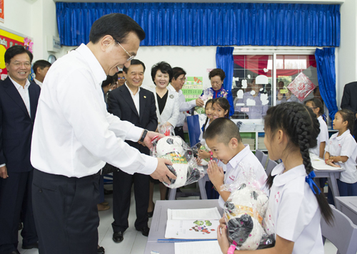 10月13日,正在泰國訪問的國務(wù)院總理李克強參觀具有110多年歷史的清邁崇華新生華立學校。這是李克強向三年級學生贈送大熊貓玩具。新華社記者 黃敬文 攝