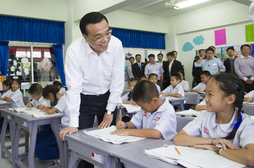 10月13日,正在泰國訪問的中國國務(wù)院總理李克強參觀具有110多年歷史的清邁崇華新生華立學校。這是李克強同正在學習寫漢字的小學三年級學生交談。新華社記者 黃敬文 攝
