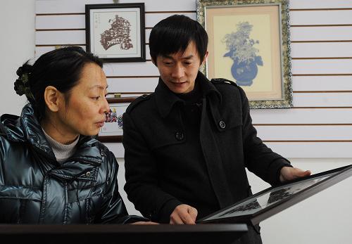 彭茂琳(左)與員工一同研究剪紙作品的裝訂方案(12月12日攝)。新華社記者 李健 攝