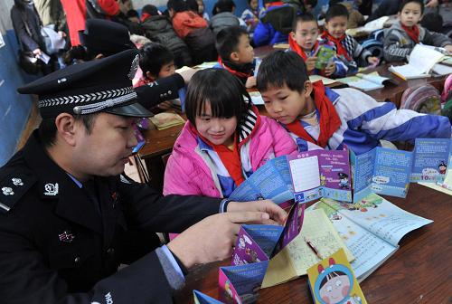 2月13日,法制輔導員在給廣西南寧市外來務工人員子弟學校——金太陽小學的孩子們講解《小學生安全手風琴》漫畫宣傳冊。新華社記者 周華 攝
