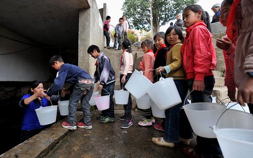 這是云南省陸良縣小百戶鎮(zhèn)老母村小學(xué)的學(xué)生們排隊等待取水(2月21日攝)。這些水是村里一個傳統(tǒng)取水點涌出的泉水,目前已經(jīng)接近枯竭。云南省曲靖市陸良縣是受到旱災(zāi)影響較重的地區(qū)之一。截至目前,持續(xù)的“三年連旱”已造成陸良縣102916人、28807頭大牲畜飲水困難;220座小型水庫和小壩塘干涸、16條河流斷流。2月21日,記者來到了陸良縣小百戶鎮(zhèn)老母村小學(xué),了解當(dāng)?shù)貛熒挠盟闆r。老母村小學(xué)地處偏遠(yuǎn)山區(qū),交通不便。學(xué)校有177名學(xué)生,其中112人寄宿。據(jù)該小學(xué)校長王云良介紹,為解決全校師生飲水難題,學(xué)校專門組織學(xué)生到村里的水源點取水,當(dāng)?shù)卣捕ㄆ谟盟退嚱o學(xué)校送水。對于有限的生活用水,學(xué)校老師指導(dǎo)學(xué)生合理利用,洗漱等生活用水按量提供。目前,當(dāng)?shù)氐暮登槿栽诔掷m(xù),學(xué)校面臨的用水困難形勢也越來越嚴(yán)峻,但當(dāng)?shù)馗刹勘硎?,即使?zāi)情再嚴(yán)重,也要保證師生用水,不讓一個學(xué)生因旱受渴,不讓一所學(xué)校因旱停課。新華社記者 藺以光 攝
