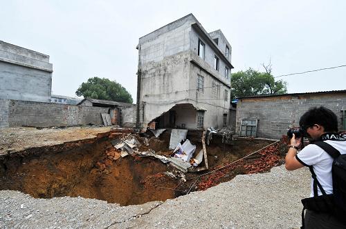 廣西柳州市柳南區(qū)帽合村一房屋底部塌陷導致的深坑比前一日擴大(5月11日攝)。新華社記者 李斌 攝