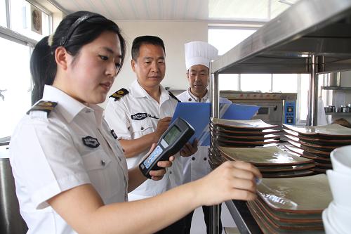 5月14日,在濱州市博興縣一家餐飲企業(yè),當(dāng)?shù)厥称匪幤繁O(jiān)督管理局執(zhí)法人員使用熒光檢測儀檢測餐具表面的潔凈度。新華社發(fā)(陳彬 攝)