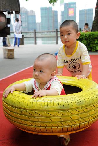 6月1日,哥哥張梓岳(后)在用輪胎做成的娛樂設(shè)施推著妹妹張梓晴玩。新華社記者 林善傳 攝