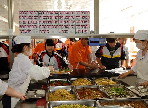 6月27日,吉林市第十三中學學生在排隊領(lǐng)取“免費午餐”,圖中窗口上方張貼的是享受此項政策的學生名單。新華社發(fā)(張楠 攝)