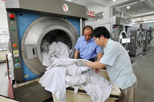 6月28日,在天津鐵路客運段洗滌廠,工作人員將臥具放入洗衣機進行洗滌。為迎接即將到來的暑期客運高峰,天津鐵路客運段洗滌廠新引進的15臺洗滌設(shè)備正式投入使用。據(jù)了解,天津鐵路客運段洗滌廠承擔(dān)著天津客運段始發(fā)列車的臥具洗滌任務(wù),每天需完成53000余件近18噸的臥具洗滌工作,引進的15臺洗滌設(shè)備提高了洗滌工作效率,保證了暑期客運期間被褥、座套的提供。新華社發(fā)(周偉 攝)