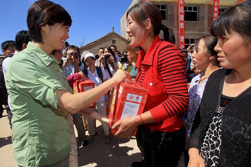 8月23日,“母親水窖”形象大使敬一丹(左一)在甘肅省定西市臨洮縣上營鄉(xiāng)舉行的“母親郵包”發(fā)放儀式上向當(dāng)?shù)貗D女發(fā)放“母親郵包”。新華社記者 李明放 攝
