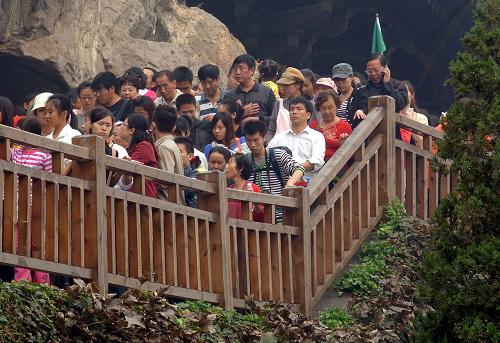 10月4日,在洛陽龍門石窟景區(qū),游客們在參觀棧道上緩緩前行。新華社記者 王頌 攝