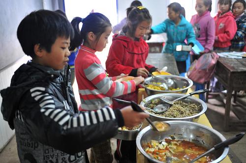 11月5日,云南彝良洛澤河鎮(zhèn)彝河村鍋圈巖小學(xué)的學(xué)生們排隊(duì)取用“營養(yǎng)午餐”。位于云南彝良洛澤河鎮(zhèn)彝河村的鍋圈巖小學(xué)在彝良地震中損壞嚴(yán)重。如今,地震已經(jīng)過去將近2個(gè)月,鍋圈巖小學(xué)的孩子在震后建起的板房小學(xué)里恢復(fù)了正常的學(xué)習(xí)生活。走進(jìn)水泥墻圍繞的校園,孩子們朗朗的讀書聲從臨時(shí)板房教室里傳出。走過6間板房教室,一片不到180平方米的空間是學(xué)生們的運(yùn)動(dòng)場(chǎng)。他們?cè)谶@里打乒乓球、做游戲,從旁邊的廚房領(lǐng)取“營養(yǎng)午餐”。11月5日,中國紅十字基金會(huì)表示將援建該小學(xué),預(yù)計(jì)明年6月將完成1500平方米的校舍建設(shè)工程。屆時(shí),鍋圈巖小學(xué)的孩子將正式告別板房,搬進(jìn)新教室上課。新華社記者 孫瑞博 攝