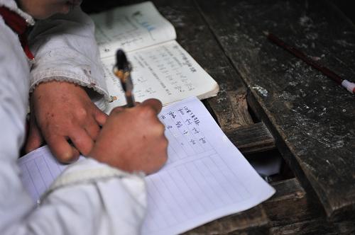 11月5日,云南彝良洛澤河鎮(zhèn)彝河村鍋圈巖小學(xué)的一名學(xué)生在課堂上寫作業(yè)。新華社記者 孫瑞博 攝
