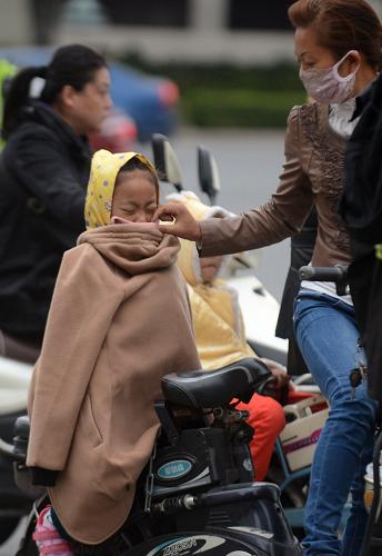 10月15日,在江蘇揚州街頭,一名家長為孩子整理衣物擋風(fēng)御寒。新華社發(fā)(孟德龍 攝)