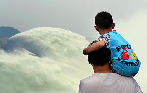 在黃河小浪底大壩出水口外,一位游客肩扛著孩子觀賞黃河調(diào)水調(diào)沙的壯觀場(chǎng)景(2013年6月22日攝)。 新華社記者 王頌 攝