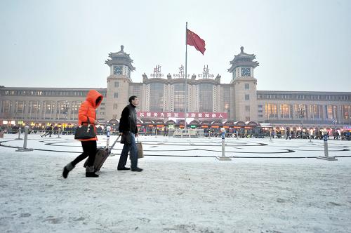 2月7日,旅客行走在被積雪覆蓋的北京站站前廣場(chǎng)上。 新華社發(fā)(王京生 攝)