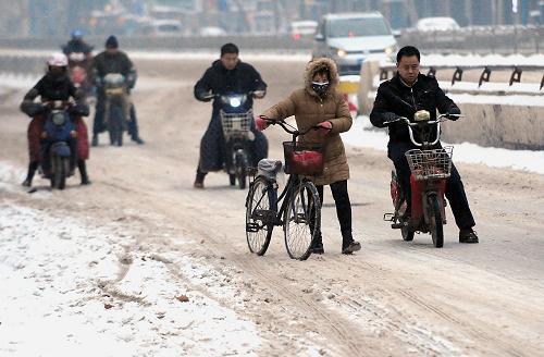 2月7日早晨,在鄭州街頭,市民騎車(chē)行駛在積雪道路上。新華社記者 王頌 攝