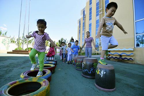 5月29日,藍(lán)天宇鋒蔡家洼幼兒園的孩子們進(jìn)行戶外活動。教具水缸和輪胎是老師從村子里買來的,并由孩子們一起在上面畫上裝飾畫。2011年9月開園的藍(lán)天宇鋒蔡家洼幼兒園,是北京城區(qū)以特色教育知名的藍(lán)天宇鋒幼兒園在密云縣蔡家洼村設(shè)立的一所分園。雖然地處農(nóng)村,這里的設(shè)施、環(huán)境和教學(xué)理念卻不輸城里。老師們還在教學(xué)上就地取材,在戶外建立蔬菜大棚,從村里找來水缸、廢棄輪胎、蒲扇、草帽等做教學(xué)用具,內(nèi)容十分豐富。經(jīng)過幾年的發(fā)展,不光吸引當(dāng)?shù)氐膬和雸@,連北京城區(qū)的不少家長也把孩子送到這里。新華社發(fā)(呂吉 攝)