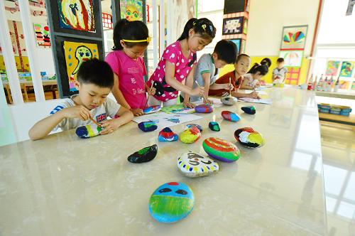 5月29日,藍(lán)天宇鋒蔡家洼幼兒園的孩子在石頭上作畫。這些石頭是老師帶著他們從幼兒園附近的小河里撿回來的。新華社發(fā)(呂吉 攝)