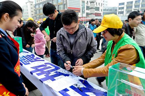 4月25日,在南昌火車站舉辦的“為雅安災(zāi)區(qū)祈福捐款”活動中,旅客在條幅上簽名,為雅安災(zāi)區(qū)祈福。新華社發(fā)