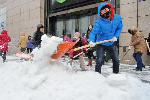 11月19日,志愿者在長(zhǎng)春市重慶路商圈清理人行步道的積雪。新華社記者 張楠 攝