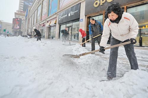 11月19日,志愿者在長(zhǎng)春市重慶路商圈清理人行步道的積雪。新華社記者 張楠 攝