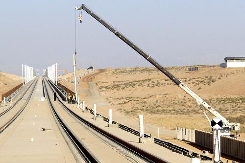 10月21日,建設(shè)者在“蘭新高鐵”新疆哈密鹽泉段用吊車吊運接觸網(wǎng)電桿。新華社發(fā)(蔡增樂 攝)