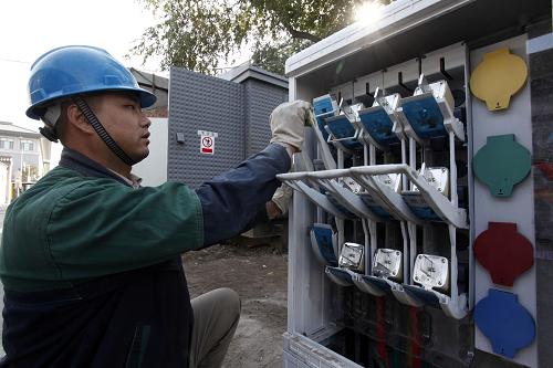10月23日,在北京市西城區(qū)西安福胡同,電力工人在對“煤改電”使用的地面式配電箱進(jìn)行調(diào)試。新華社發(fā)(楊樂 攝)