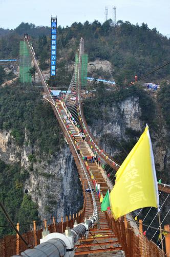 施工中的張家界大峽谷玻璃橋（12月3日攝）。12月3日，隨著最后一片重達41噸加勁梁的精準(zhǔn)吊裝，湖南張家界大峽谷玻璃橋鋼箱梁成功合龍。據(jù)悉，張家界大峽谷玻璃橋總長430米、寬6米，橋面距離谷底相對高度約300米。橋面全部采用透明玻璃鋪設(shè)，最大游客容量為800人。目前，大橋建設(shè)進入施工尾期，預(yù)計2016年“五一”節(jié)前對外開放。新華社記者 龍弘濤 攝