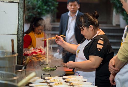 重慶胖妹面莊老板高維在面鍋前專注地工作（11月24日攝）。37歲的高維從最初的擺攤到擁有自己的鋪面、從創(chuàng)業(yè)的艱難到蜚聲全國(guó)、從一個(gè)來(lái)自農(nóng)村的打工妹成長(zhǎng)為重慶知名面店的老板，她和丈夫花了20多年的時(shí)間。如今，她依然每天站在熱氣騰騰的面鍋前為每一位光顧她面店的食客挑面服務(wù)。
