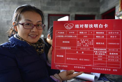 12月16日，湖北省宣恩縣委宣傳部“扶貧家長”魏小玲展示精準扶貧“結對幫扶明白卡”。新華社發(fā)（宋文 攝）