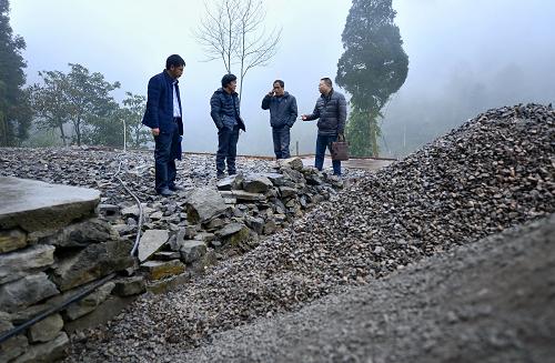 12月22日，湖北省宣恩縣縣辦公室“扶貧家長”譚發(fā)軍（右一）在椒園鎮(zhèn)石馬村貧困農民曾召毅（左二）的房屋整修現(xiàn)場了解施工進度。新華社發(fā)（宋文 攝）