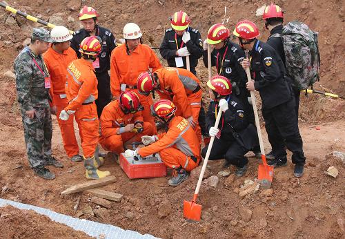 12月23日，天狼救援隊(duì)（黑衣）和武警官兵一起使用生命測(cè)試儀。在深圳滑坡災(zāi)害發(fā)生后，除了解放軍和武警部隊(duì)的救援力量，災(zāi)害現(xiàn)場(chǎng)還活躍著多支志愿者專(zhuān)業(yè)救援隊(duì)伍。他們與解放軍和武警部隊(duì)相配合，用專(zhuān)業(yè)的技術(shù)手段和技術(shù)能力開(kāi)展救援。新華社記者 殷剛 攝