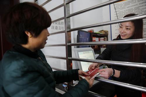 12月27日，在河南省寶豐縣趙莊鎮(zhèn)袁莊村農(nóng)民金融自助服務(wù)點，村民岳麗花（左）在辦理糧食直補金領(lǐng)取業(yè)務(wù)。