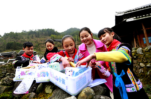 1月12日，湖南省城步苗族自治縣長安營鄉(xiāng)民族中心學(xué)校的學(xué)生在回家路上和老師（右二）察看愛心禮物。當(dāng)日，中國兒童少年基金會攜手安利公益基金會，來到湖南省城步苗族自治縣長安營鄉(xiāng)民族中心學(xué)校，向苗族侗族貧困兒童及留守兒童發(fā)放“HELLO小孩”愛心套餐?！癏ELLO小孩”愛心套餐公益項目由中國兒童少年基金會推出，主要為困難兒童提供多種學(xué)習(xí)生活必需品。此次活動將投入50萬元定向為湖南貧困地區(qū)兒童贈送2500套“HELLO小孩”日常套餐，并為這些孩子普及營養(yǎng)知識，幫助他們健康成長。新華社記者 潘旭 攝