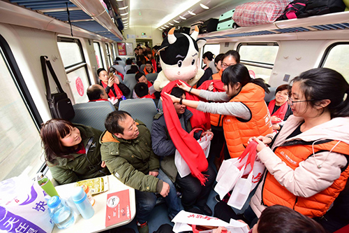 1月28日，“幸福列車”工作人員為旅客送上祝福的紅圍巾。