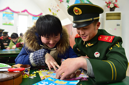 1月29日，武警戰(zhàn)士楊盼望與兒童福利院的孩子玩拼圖。